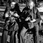 Couple assis sur un banc captivé par leurs téléphones respectifs